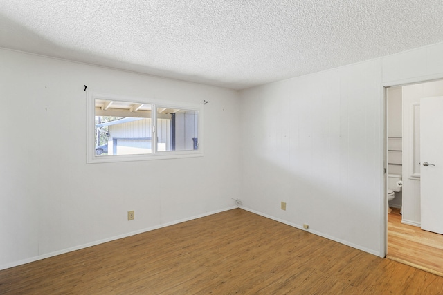 empty room with wood-type flooring and a textured ceiling