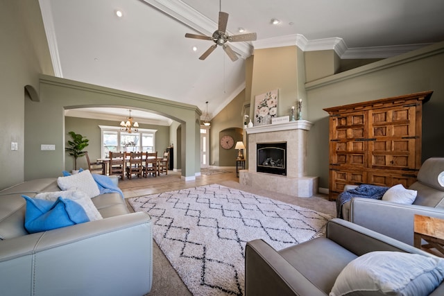 living room with ceiling fan with notable chandelier, high vaulted ceiling, crown molding, and a high end fireplace