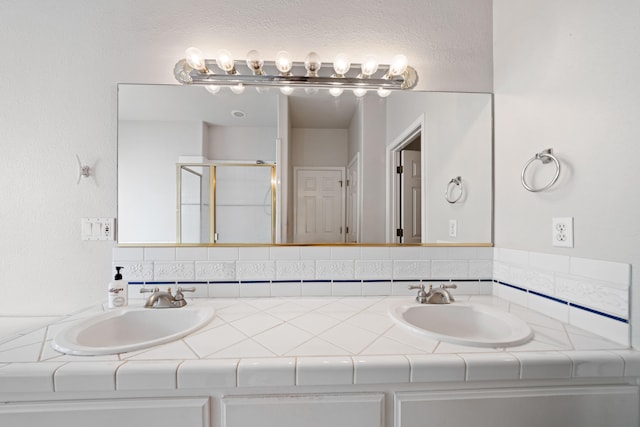 bathroom featuring double vanity, a stall shower, and a sink