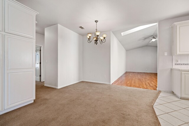 interior space with visible vents, lofted ceiling with skylight, light carpet, light tile patterned flooring, and ceiling fan with notable chandelier