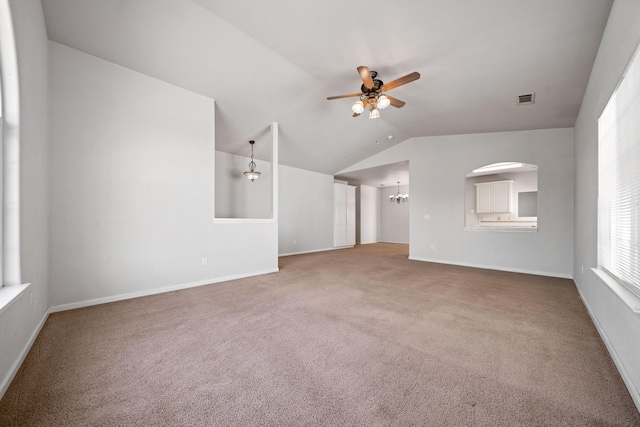 unfurnished living room with baseboards, visible vents, lofted ceiling, carpet floors, and ceiling fan with notable chandelier