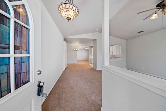 hall with carpet floors, lofted ceiling, visible vents, an inviting chandelier, and baseboards