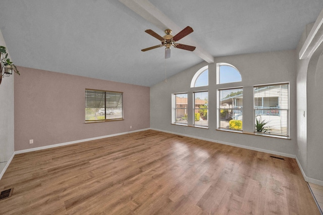 empty room featuring ceiling fan, lofted ceiling with beams, and hardwood / wood-style flooring