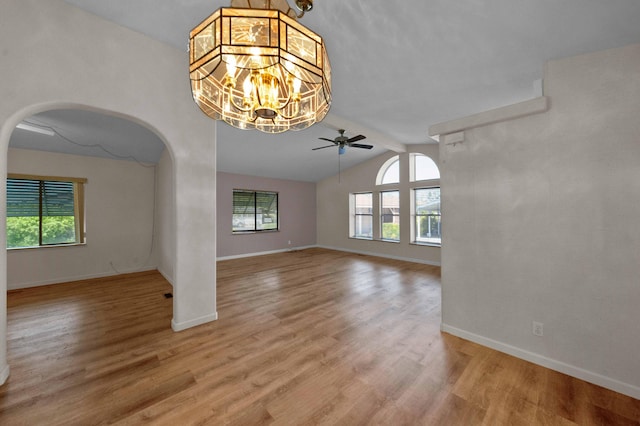 unfurnished living room featuring ceiling fan with notable chandelier, lofted ceiling with beams, and hardwood / wood-style floors