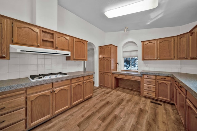 kitchen with hardwood / wood-style flooring, tasteful backsplash, vaulted ceiling, and white gas stovetop