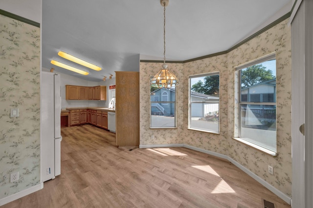 unfurnished dining area featuring light hardwood / wood-style floors, a chandelier, and crown molding