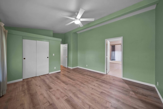 unfurnished bedroom with ensuite bathroom, vaulted ceiling, ceiling fan, hardwood / wood-style flooring, and a closet