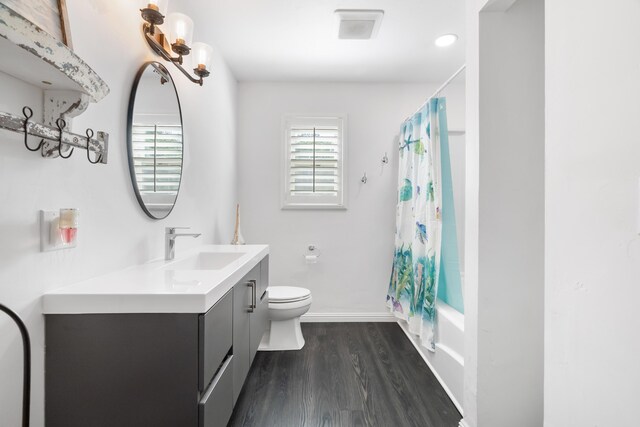 full bathroom featuring vanity, hardwood / wood-style flooring, shower / bath combo with shower curtain, and toilet