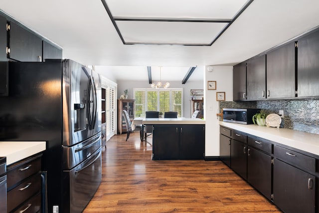 kitchen featuring appliances with stainless steel finishes, dark wood-type flooring, tasteful backsplash, hanging light fixtures, and beam ceiling