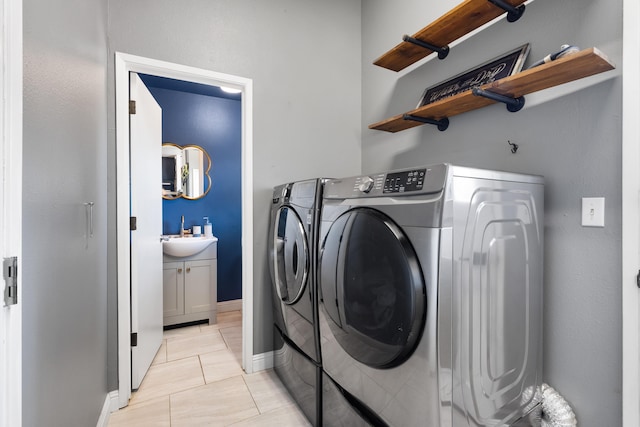 washroom featuring washing machine and dryer, light tile patterned floors, and sink