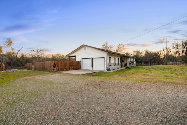 property exterior at dusk with a garage and a yard