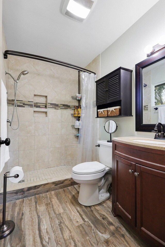 bathroom with walk in shower, vanity, toilet, and hardwood / wood-style flooring