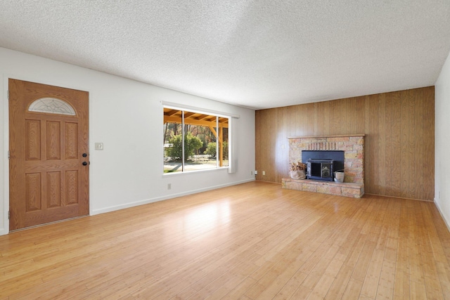 unfurnished living room with wooden walls, light hardwood / wood-style floors, and a textured ceiling