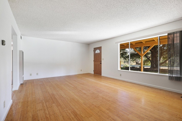 unfurnished room with a textured ceiling and light hardwood / wood-style floors