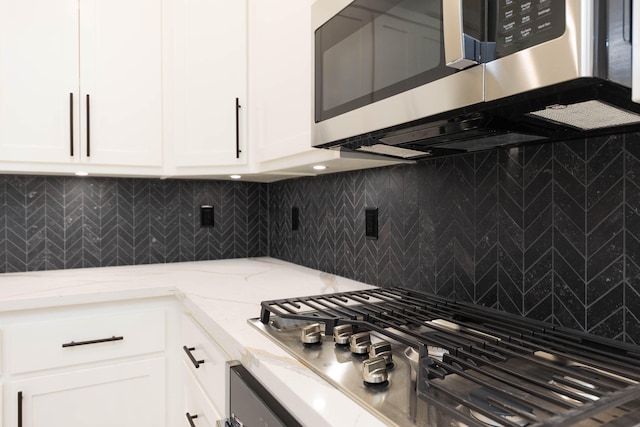 kitchen featuring appliances with stainless steel finishes, light stone counters, tasteful backsplash, and white cabinetry