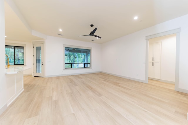 unfurnished living room featuring ceiling fan and light wood-type flooring