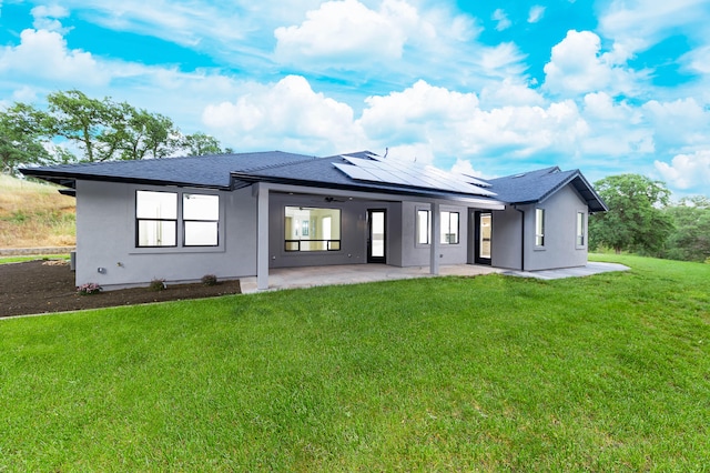 back of property with a patio area, a yard, and solar panels