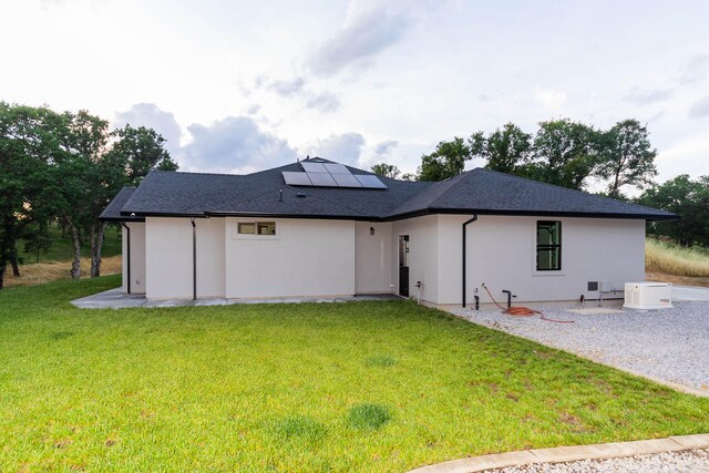 rear view of property with solar panels and a yard