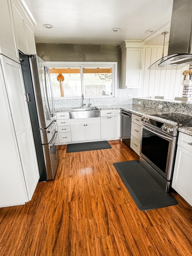 kitchen featuring wall chimney range hood, white cabinetry, stainless steel appliances, hardwood / wood-style flooring, and sink