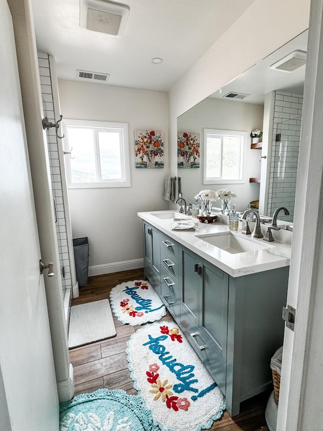 bathroom featuring wood-type flooring, oversized vanity, and dual sinks