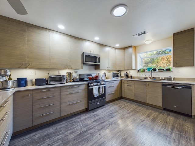 kitchen with appliances with stainless steel finishes, sink, and dark hardwood / wood-style flooring