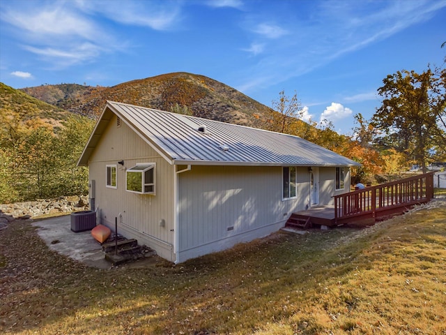 back of property featuring a yard, a deck with mountain view, and central AC unit