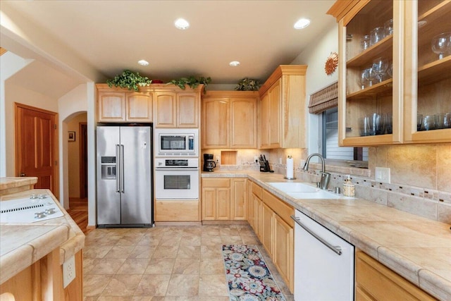 kitchen with tile counters, stainless steel appliances, sink, tasteful backsplash, and light tile floors