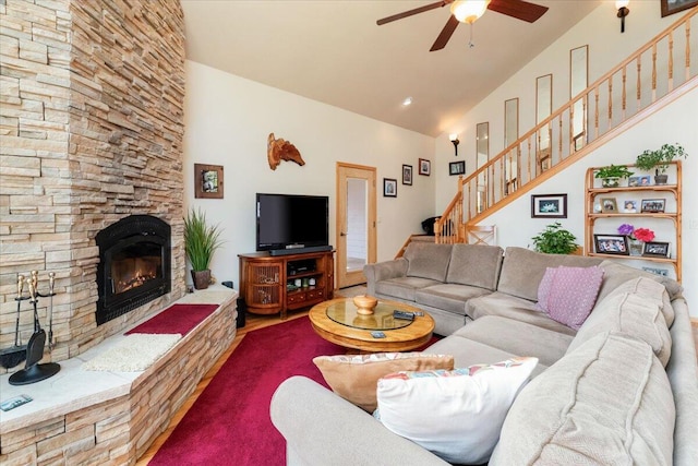 living room featuring ceiling fan, a fireplace, and lofted ceiling