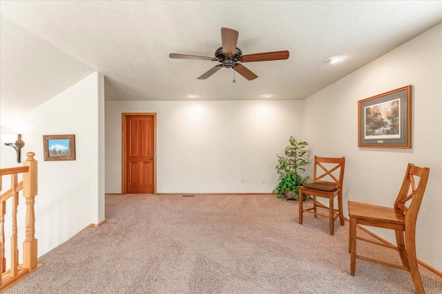 sitting room with ceiling fan and light colored carpet