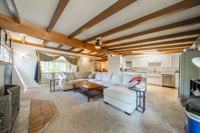 carpeted living room with plenty of natural light, beam ceiling, sink, and ceiling fan