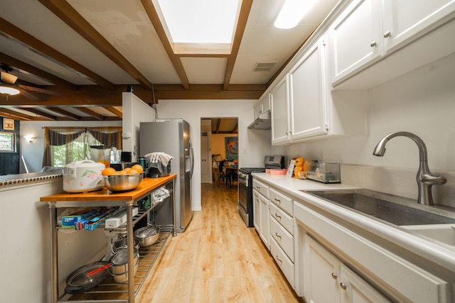 kitchen featuring white cabinetry, sink, light hardwood / wood-style flooring, beamed ceiling, and appliances with stainless steel finishes