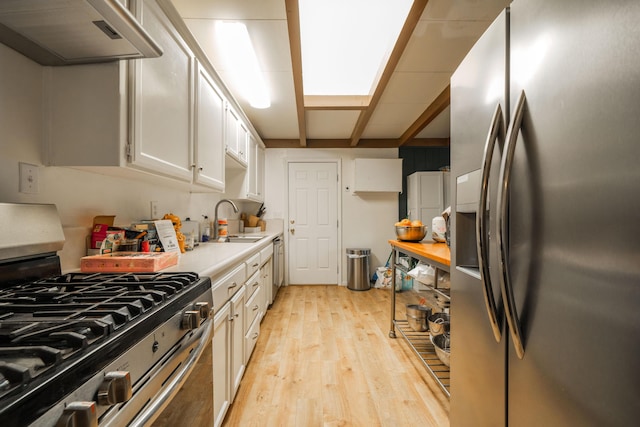 kitchen with white cabinetry, sink, extractor fan, appliances with stainless steel finishes, and light wood-type flooring