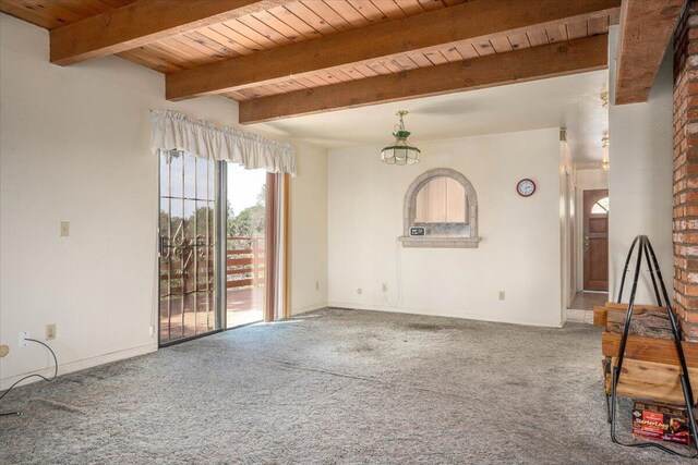 unfurnished living room featuring beam ceiling, carpet flooring, and brick wall