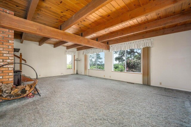 unfurnished living room featuring a wood stove, carpet floors, plenty of natural light, and brick wall