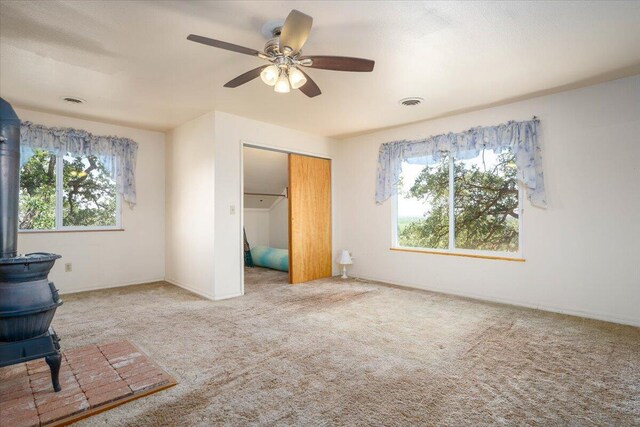 interior space featuring light carpet, a closet, ceiling fan, and multiple windows