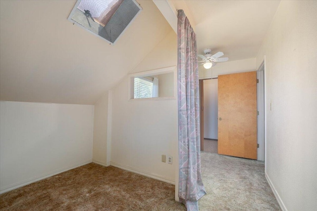 bonus room with ceiling fan, light colored carpet, and vaulted ceiling with skylight