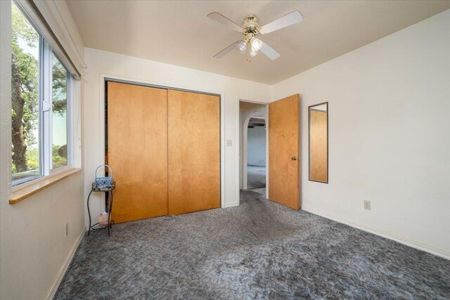 unfurnished bedroom with ceiling fan, a closet, and carpet floors