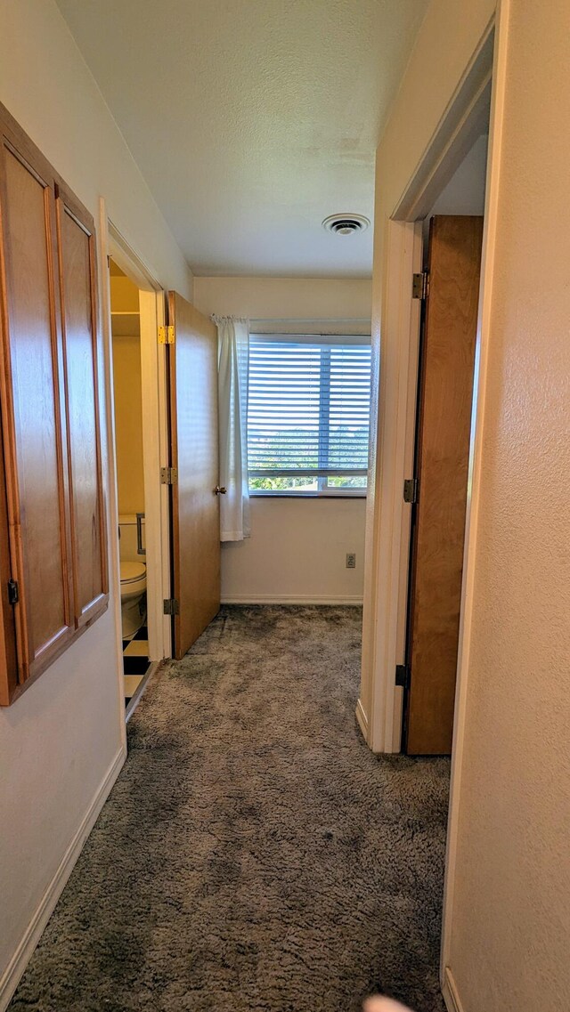 corridor featuring dark colored carpet