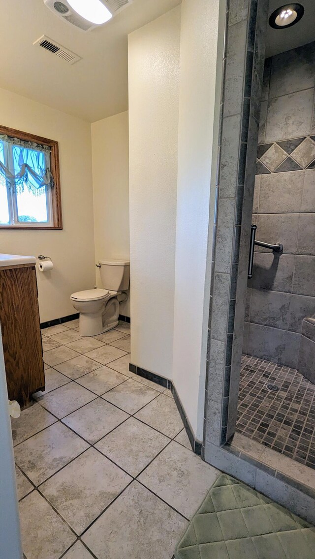 bathroom featuring tile patterned flooring, toilet, and tiled shower