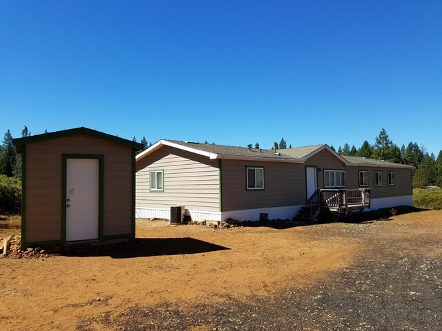 back of house featuring a shed and central AC