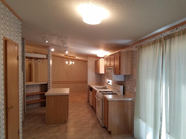 kitchen featuring white appliances, rail lighting, a textured ceiling, light tile floors, and sink