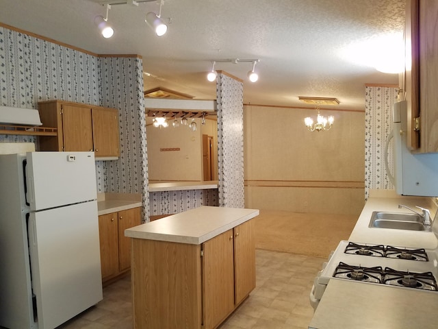 kitchen featuring sink, range, track lighting, and white fridge