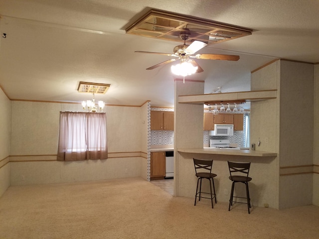 kitchen with kitchen peninsula, backsplash, ceiling fan with notable chandelier, white appliances, and a breakfast bar