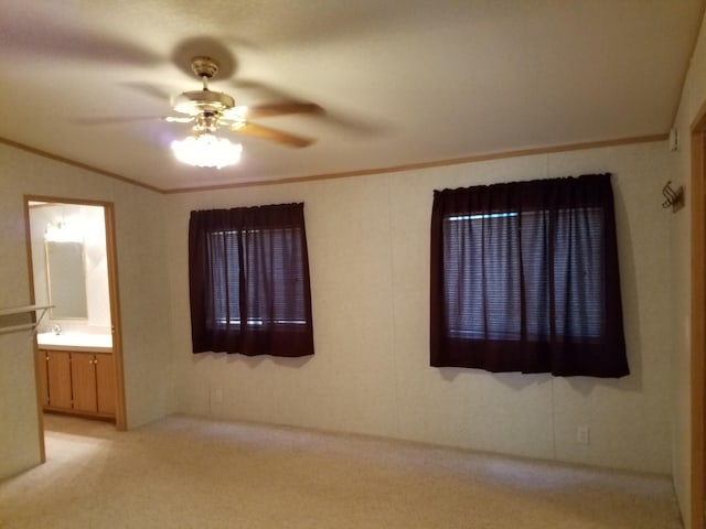 carpeted spare room with crown molding, vaulted ceiling, and ceiling fan
