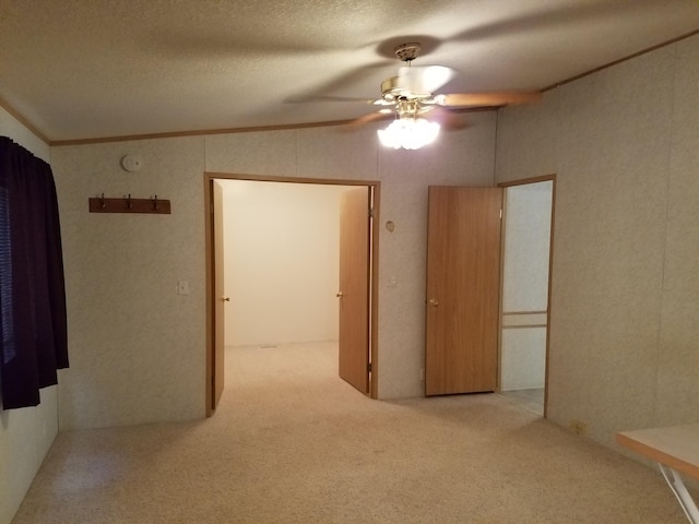 carpeted empty room with ornamental molding, ceiling fan, and a textured ceiling