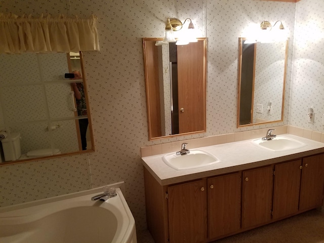 bathroom with vanity, a tub to relax in, and toilet