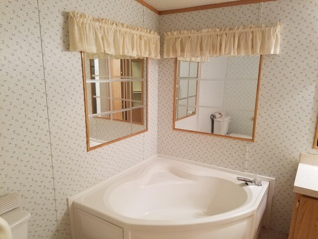 bathroom featuring vanity, toilet, and a bath to relax in