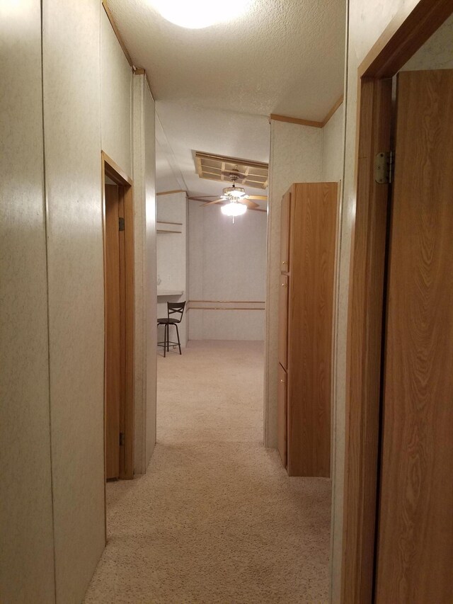 corridor with a textured ceiling and light colored carpet