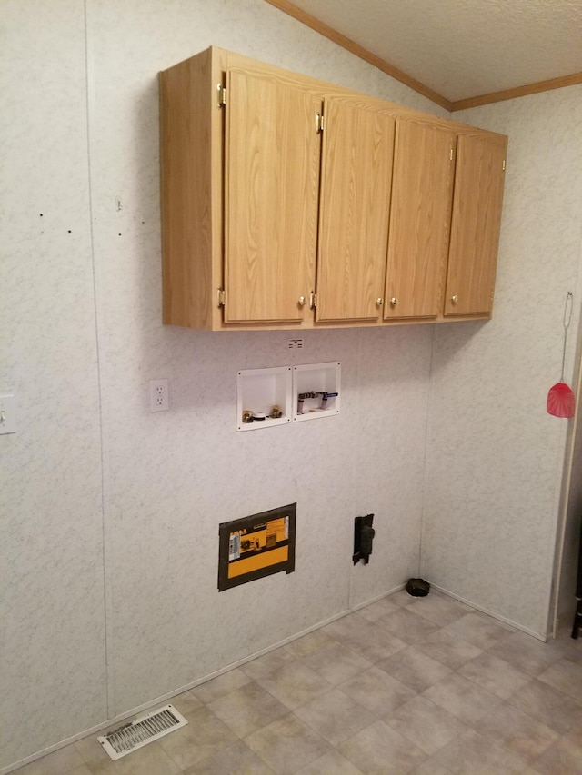 clothes washing area featuring tile floors, ornamental molding, washer hookup, and cabinets