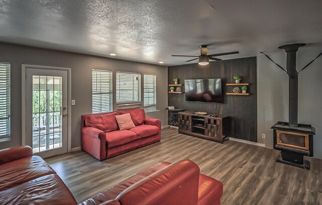 living room with hardwood / wood-style flooring, plenty of natural light, a wood stove, and ceiling fan